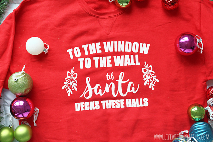 "To the Window, to the Wall, 'Til Santa Decks these Halls" Christmas parody sweatshirt that you can DIY! All you need is a Cricut, vinyl, screen printing supplies, and a sweatshirt to make this hilarious holiday sweater.